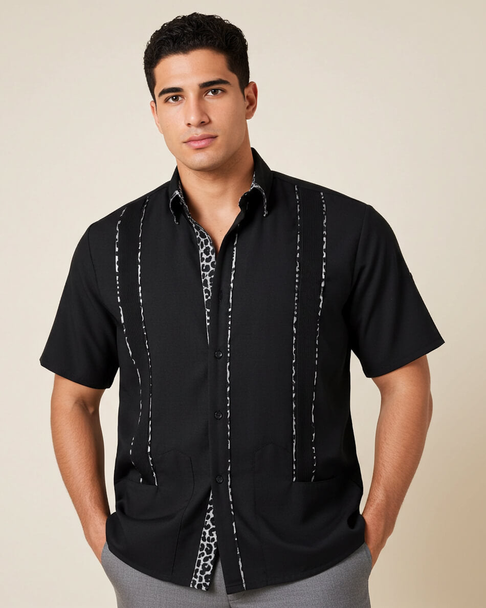Man wearing a black guayabera shirt with white patterns on a beige background