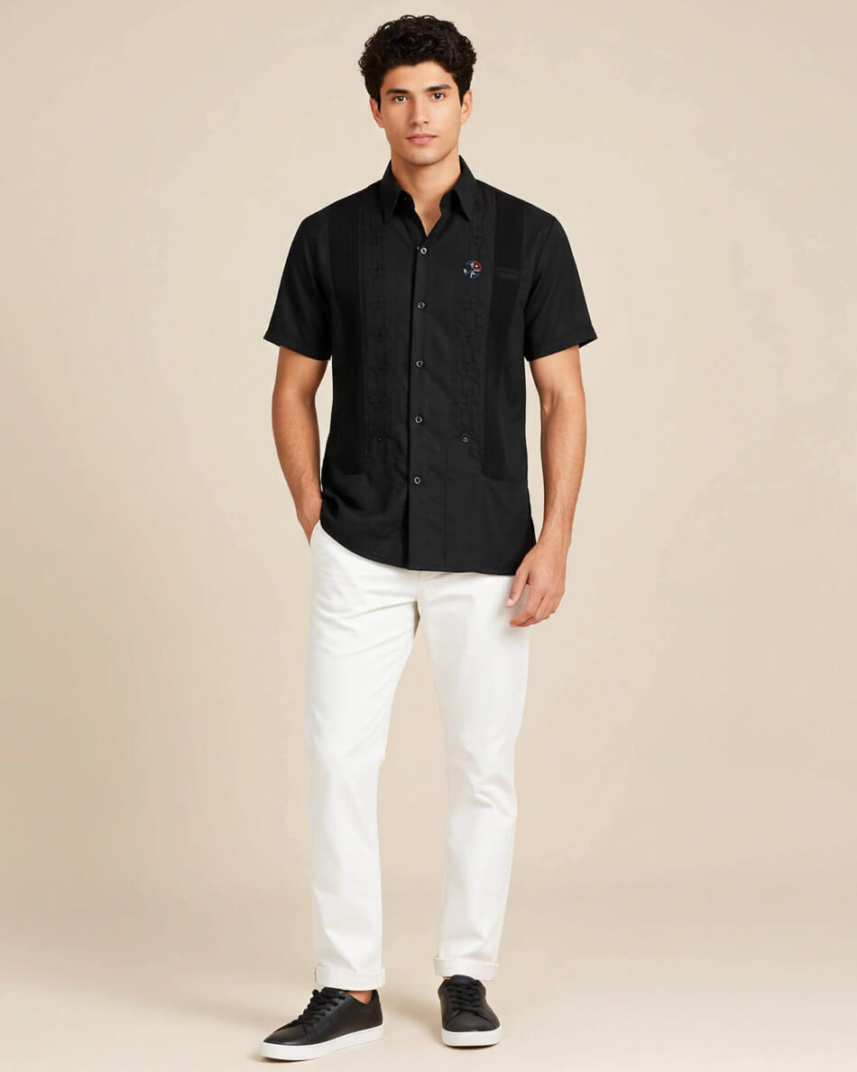 Man wearing a black short-sleeve shirt and white pants on a beige background