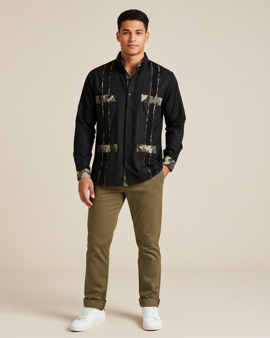 Man wearing a black guayabera shirt with camouflage patterns and green pants on a beige background