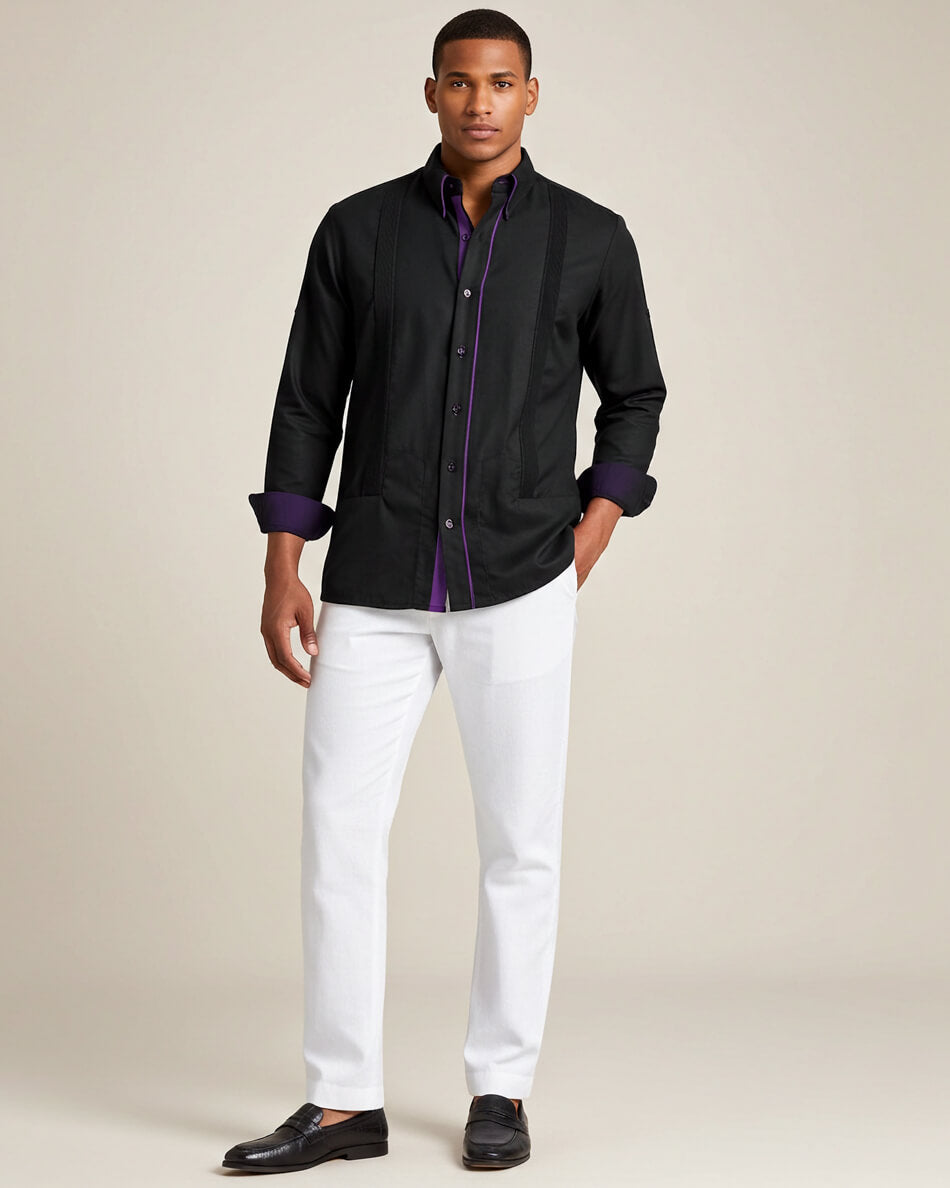 Man wearing a black long-sleeve guayabera with purple accents and white pants on a beige background