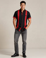 Man wearing a black guayabera shirt with red accents and gray pants on a beige background