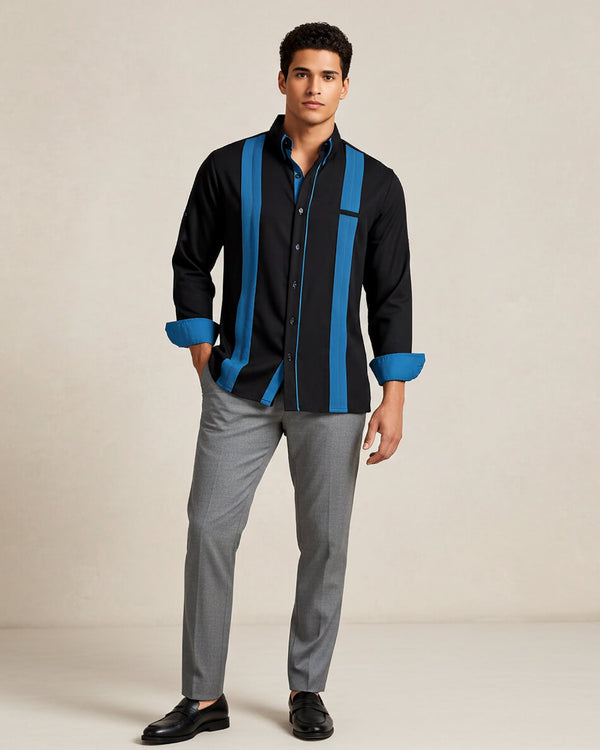 Man wearing a black guayabera shirt with turquoise accents and gray pants on a beige background