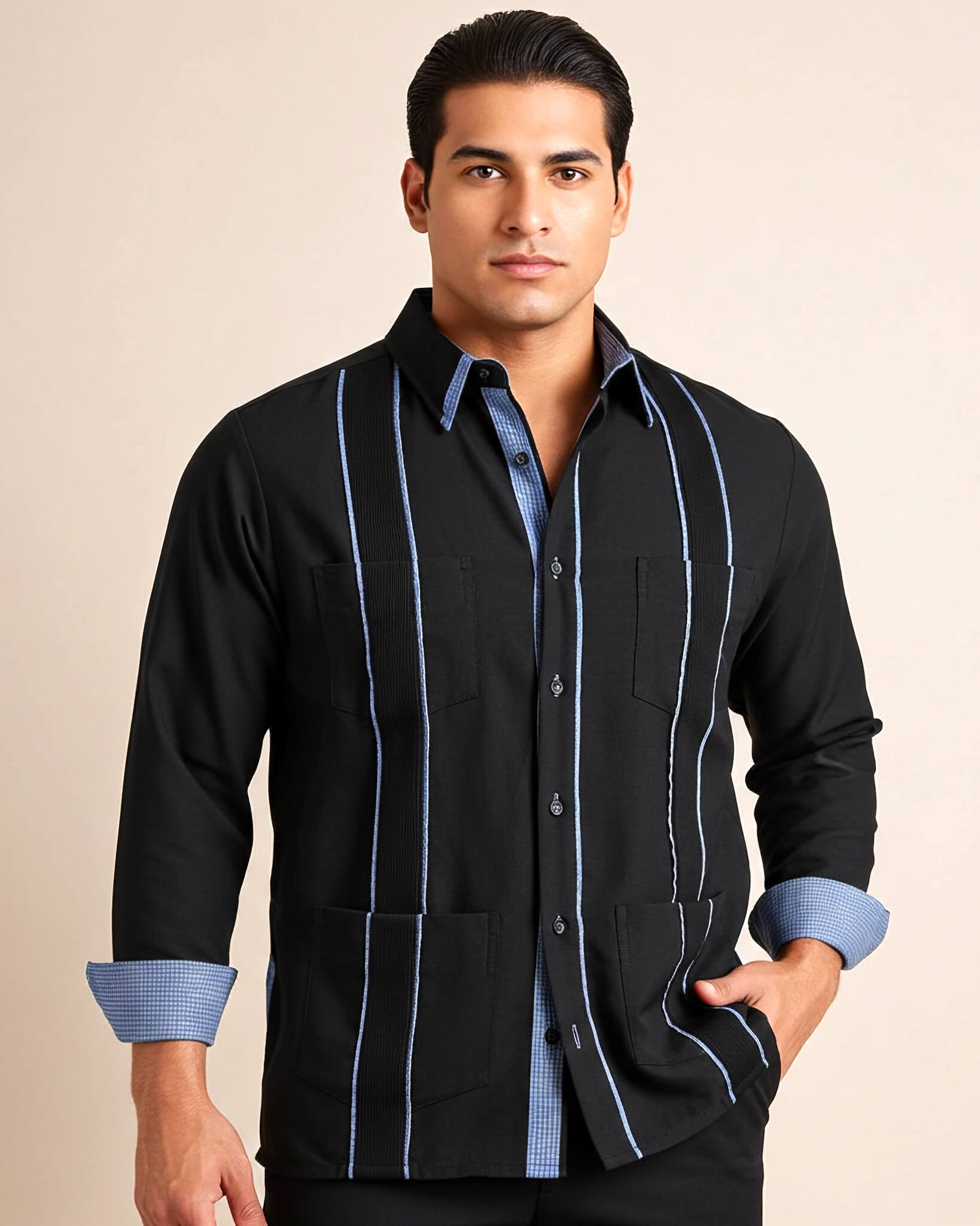 Man wearing a black guayabera shirt with blue gingham accents and cuffs on a beige background