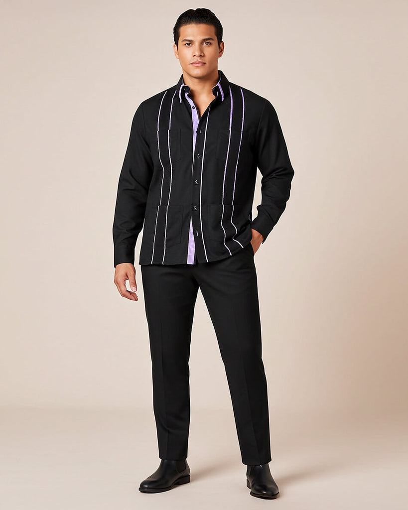 Man wearing a black guayabera shirt with purple gingham accents and cuffs on a beige background