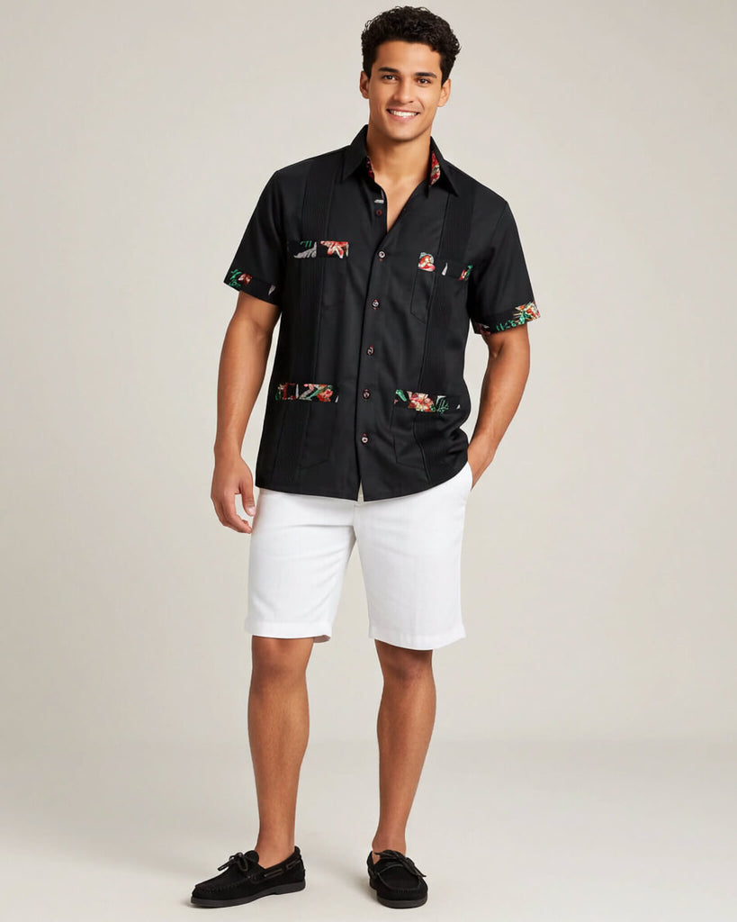Man wearing a black guayabera shirt and white shorts on a plain background