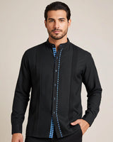 Man wearing a black guayabera shirt with turquoise gingham accents on a beige background