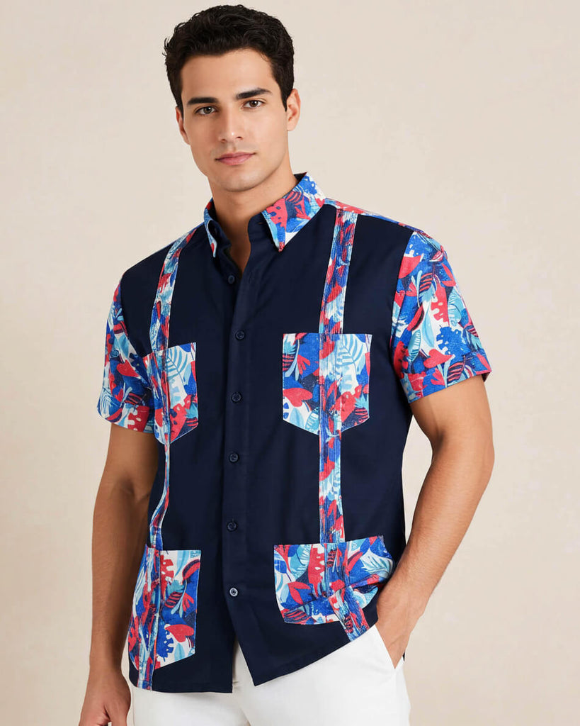 Man wearing a navy guayabera shirt with colorful floral patterns on a beige background