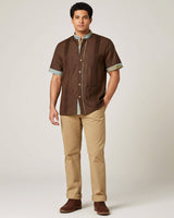 Man wearing a brown shirt and beige pants against a white background