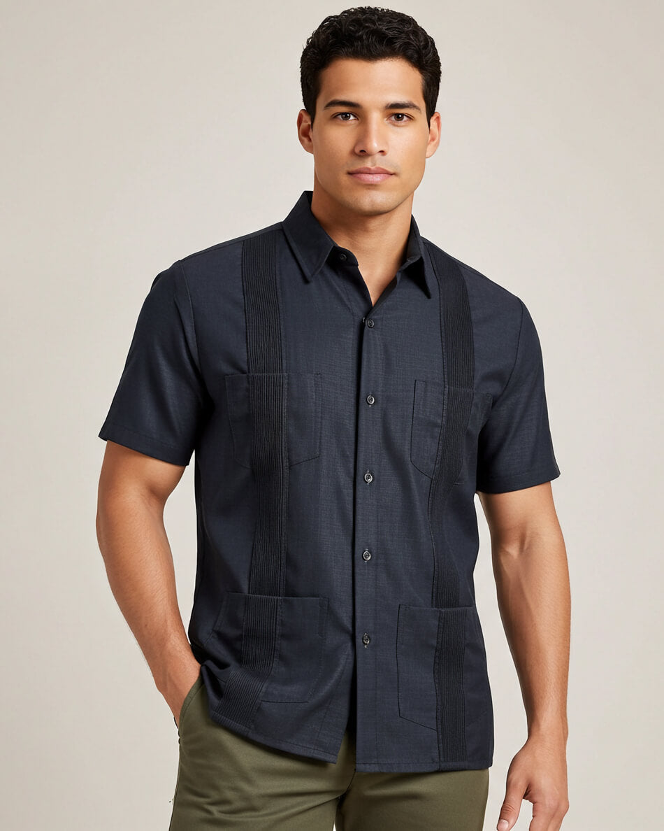 Man wearing a dark grey short-sleeve guayabera shirt on a beige background