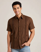 Man wearing a brown short-sleeve guayabera shirt with a neutral background