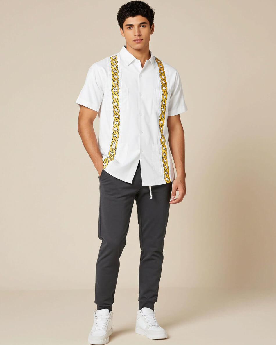 Man wearing a white shirt with gold cuban link embroidery and dark pants on a beige background