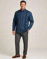 Man wearing a deep teal shirt and gray pants on a beige background