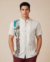 Man wearing a beige guayabera shirt with detailed dreamcatcher embroidery and maroon pants on a beige background