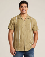 Man wearing a khaki guayabera button-up shirt with white stripes on a beige background