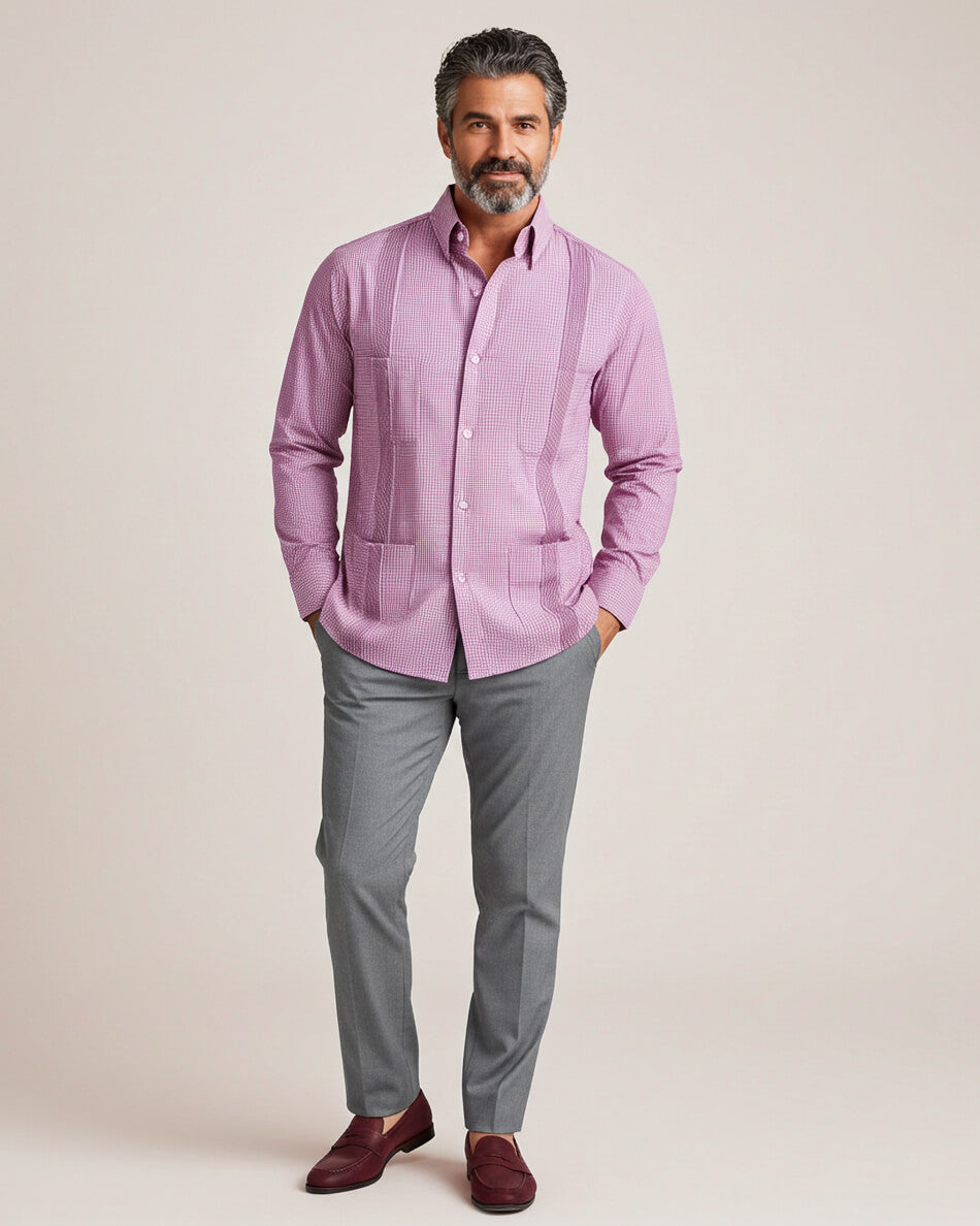 Man wearing a pink guayabera shirt and gray pants against a beige background