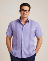 Man wearing a purple checkered guayabera shirt against a beige background