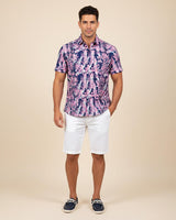 Man wearing a patterned shirt and white shorts on a beige background