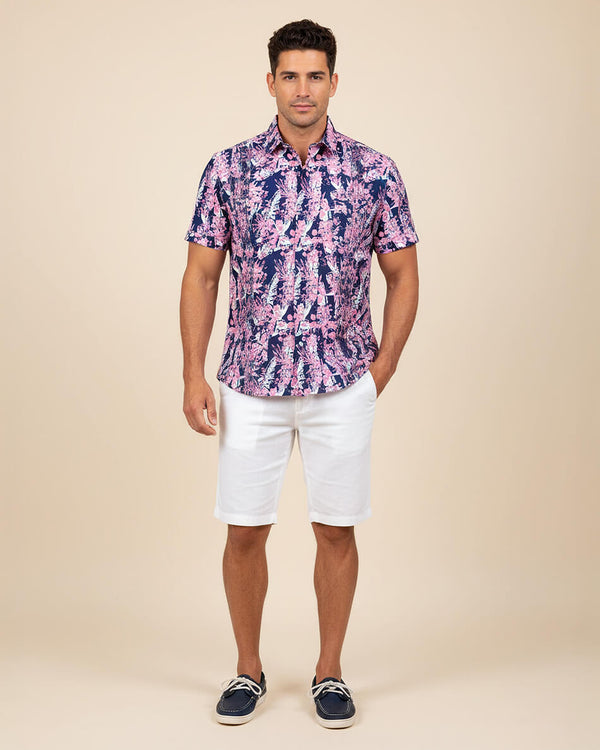 Man wearing a patterned shirt and white shorts on a beige background