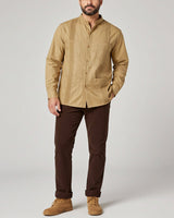 Man wearing a khaki guayabera shirt and brown pants on a plain background