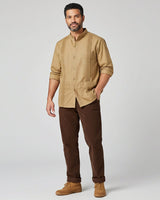 Man wearing a khaki guayabera shirt and brown pants on a white background