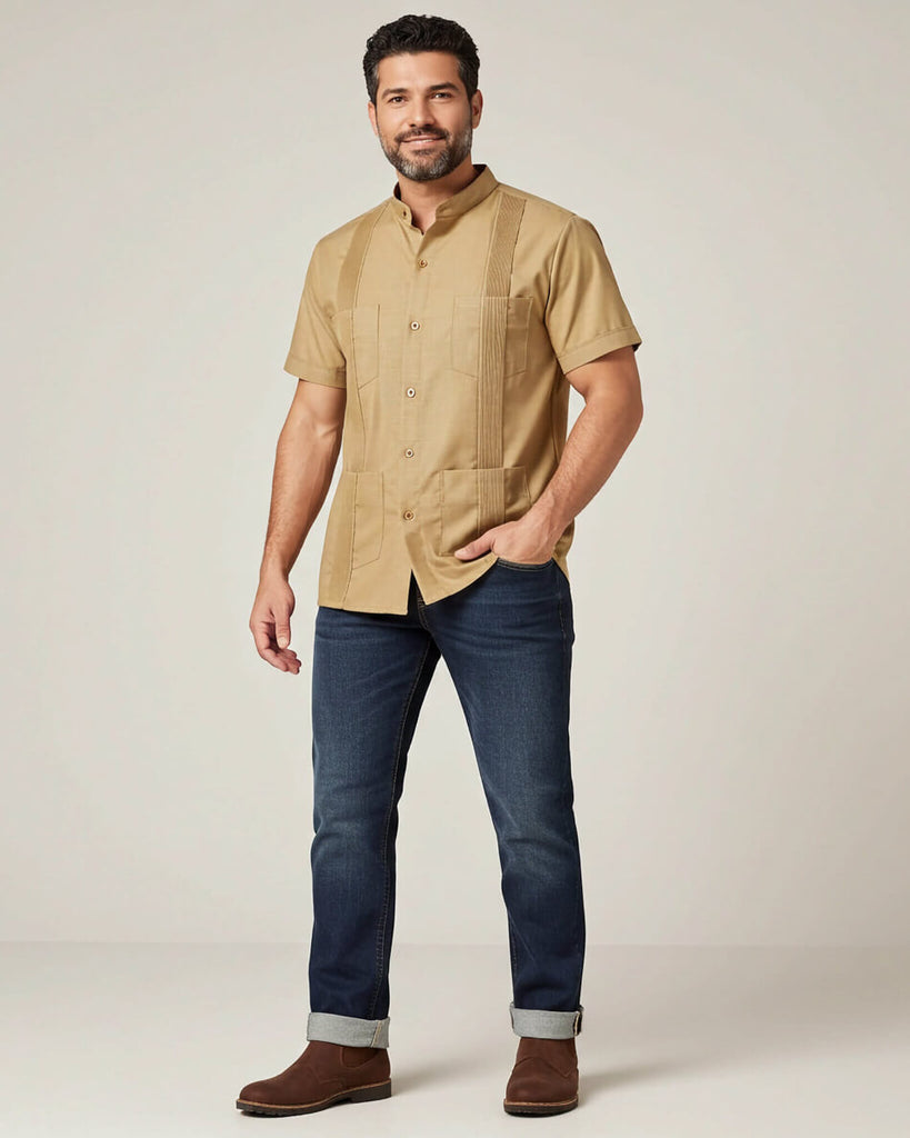 Man wearing a khaki short-sleeve shirt, blue jeans, and brown shoes on a plain background