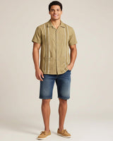 Man wearing a khaki guayabera button-up guayabera shirt with white stripes on a beige background