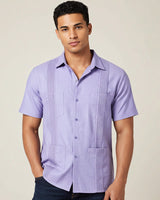 Man wearing a light purple guayabera short-sleeve shirt against a beige background