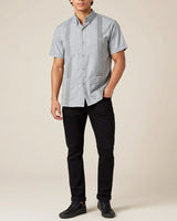 Person wearing a light grey short-sleeve shirt with black pants on a beige background