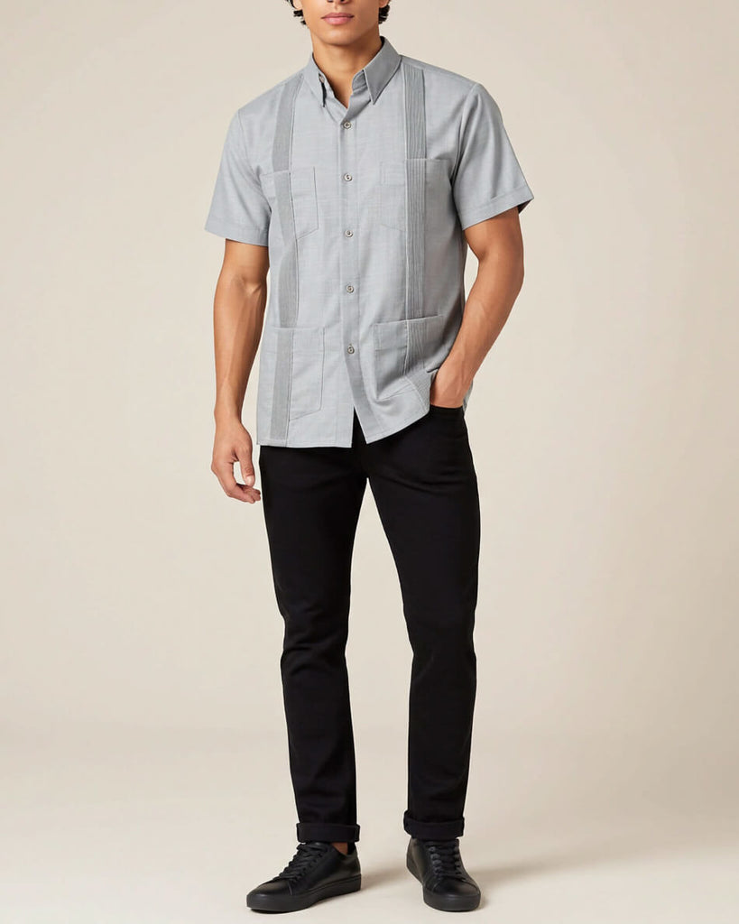 Person wearing a light grey short-sleeve shirt with black pants on a beige background