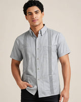 Man wearing a light gray short-sleeve guayabera shirt with pintuck pleats on a beige background