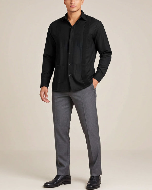 Man wearing a black guayabera shirt and gray pants on a beige background