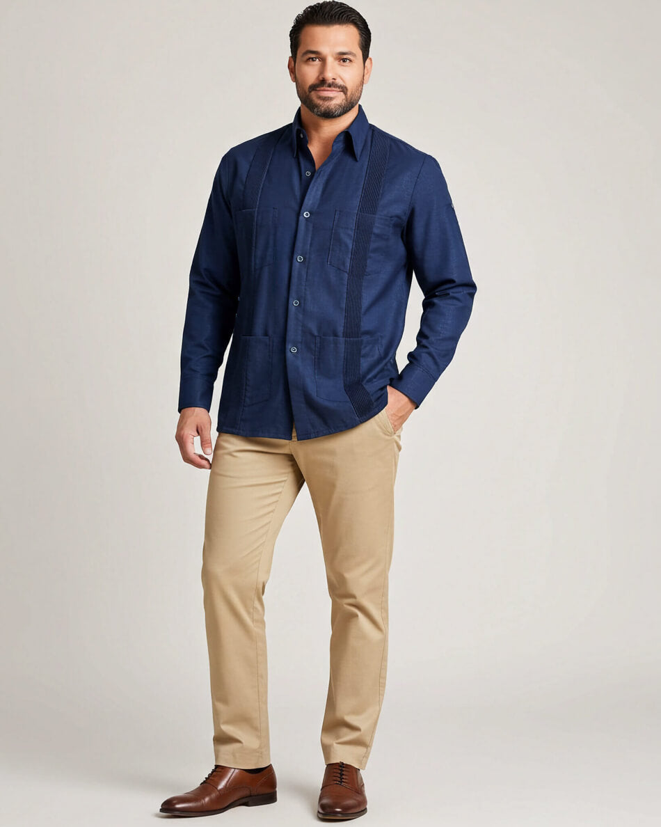 Man wearing a navy guayabera shirt and beige pants on a light gray background