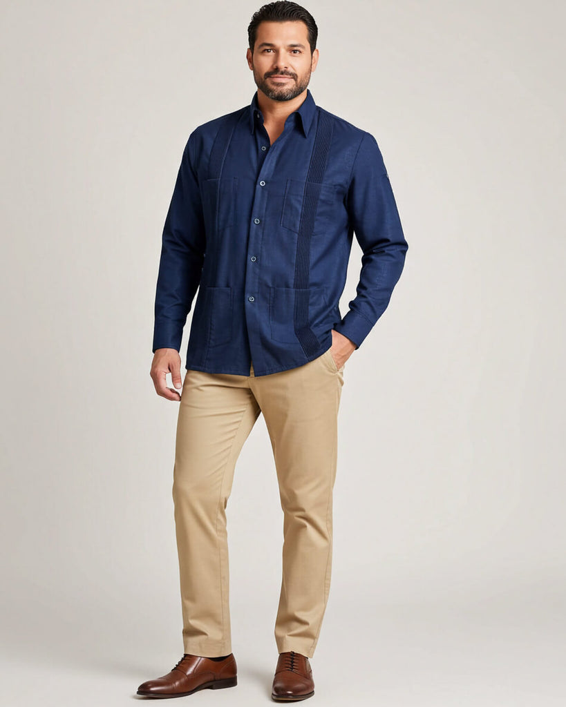 Man wearing a navy guayabera shirt and beige pants on a light gray background