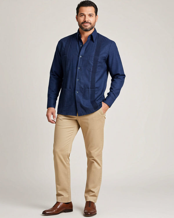 Man wearing a navy guayabera shirt and beige pants on a light gray background