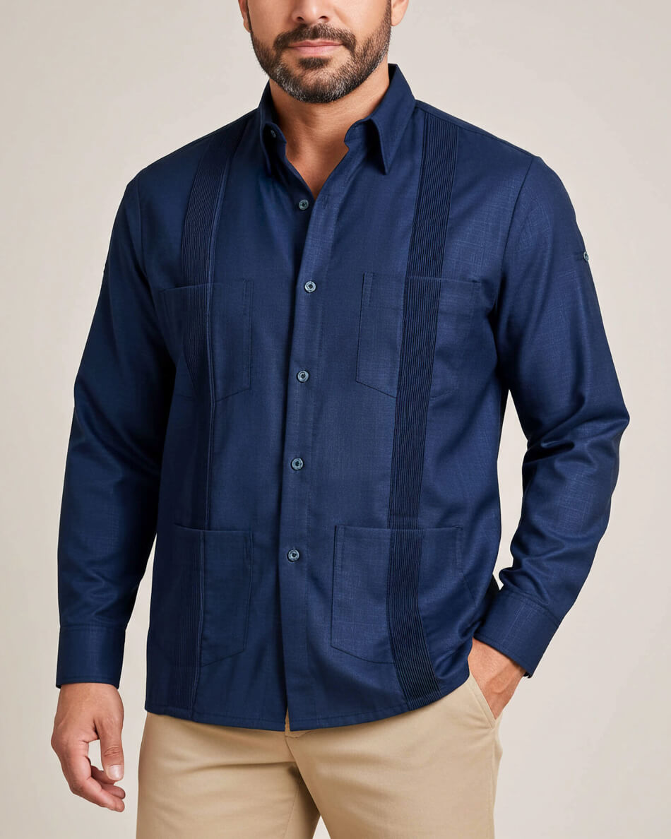 Man wearing a navy blue guayabera shirt with beige pants on a plain background
