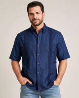 Man wearing a navy blue guayabera shirt with four pockets against a beige background