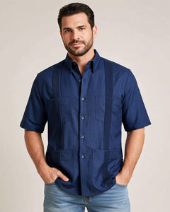 Man wearing a navy blue guayabera shirt with four pockets against a beige background