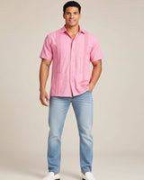 Man wearing a pink guayabera shirt and blue jeans on a beige background
