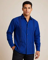 Man wearing a blue button-up guayabera shirt with long sleeves against a beige background