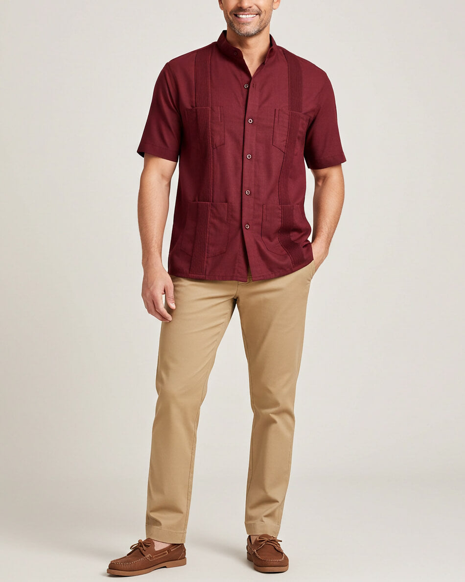 Man wearing a maroon short-sleeve guayabera shirt and beige pants on a plain background