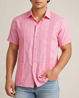 Man wearing a pink guayabera short-sleeve shirt with a neutral background