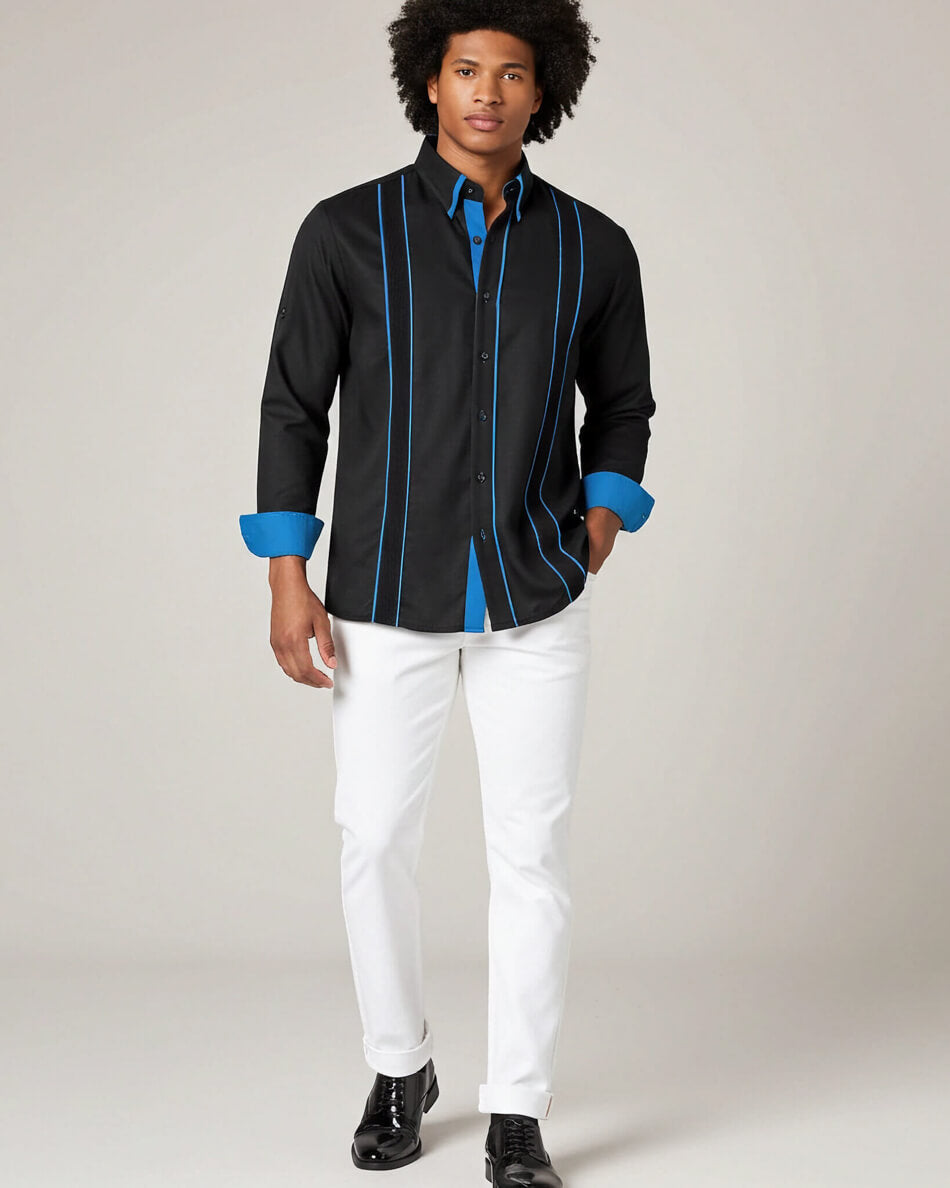 Man wearing a black guayabera shirt with blue accents and white pants on a plain background