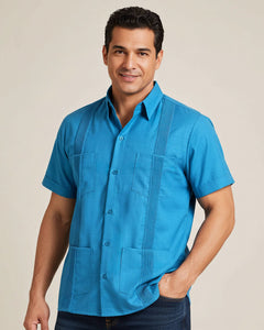 Man wearing a turquoise guayabera shirt against a beige background