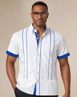 Man wearing a white guayabera shirt with blue accents on a beige background