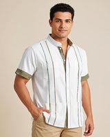 Man wearing a white guayabera shirt with green camo accents on a beige background