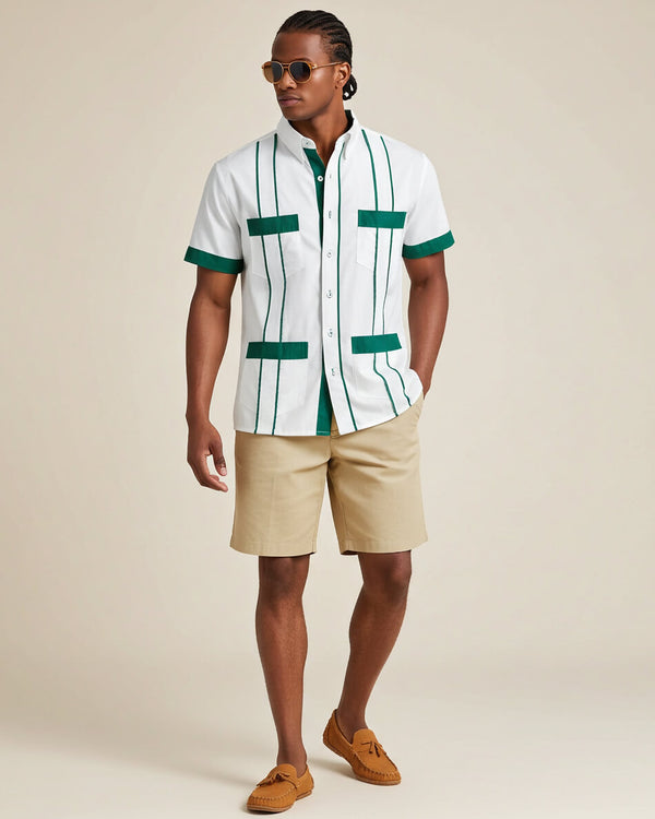 Man wearing a white guayabera shirt with green accents and beige shorts on a beige background