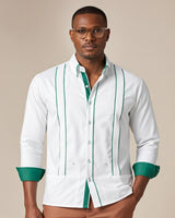 Man wearing a white guayabera shirt with green accents on a beige background
