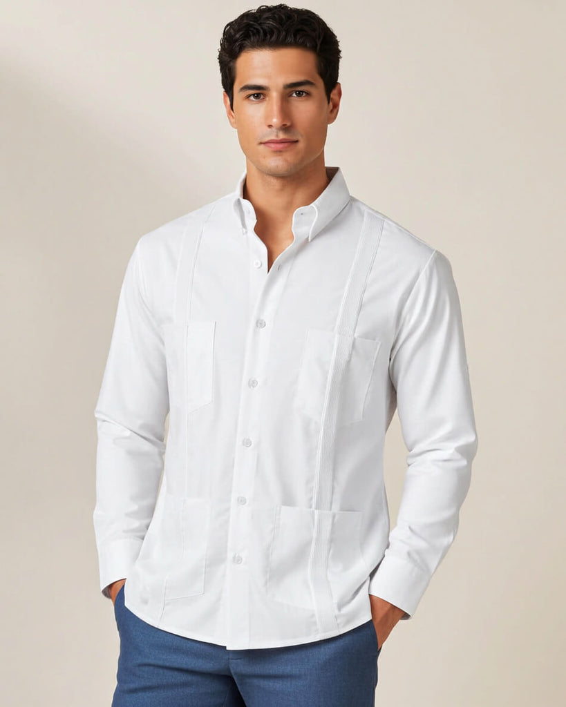 Man wearing a white button-up guayabera shirt and blue pants against a beige background