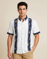 Man wearing a white guayabera shirt with navy and floral accents on a beige background