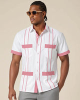 Man wearing a white guayabera shirt with pink accents and sunglasses on a beige background